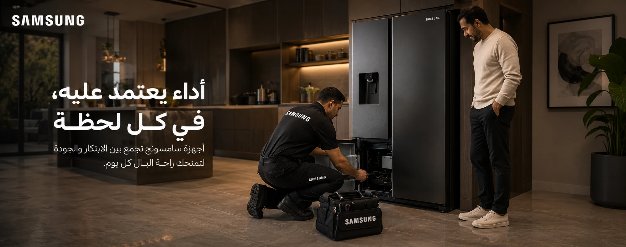 فني صيانة يحمل شعار سامسونج أثناء فحص ثلاجة سامسونج داخل مطبخ حديث وبجواره عميل يتابع الصيانة